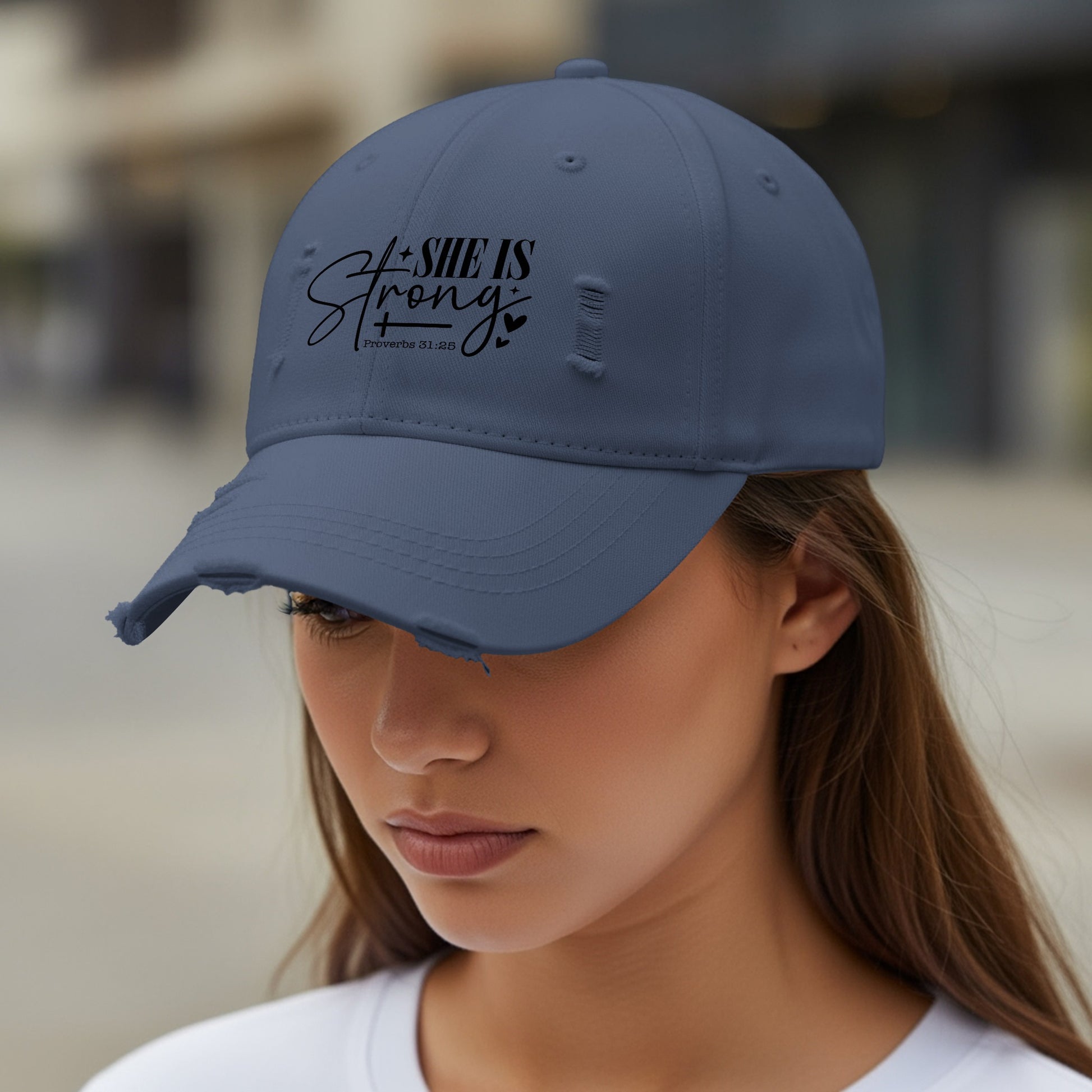 Distressed navy baseball cap with "SHE IS Strong" and Proverbs 31:25 text.