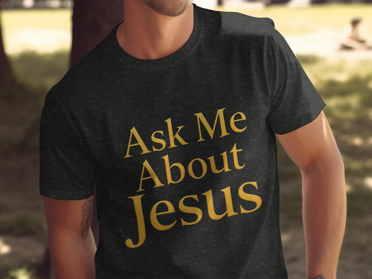Dark gray t-shirt with gold text that reads "Ask Me About Jesus."