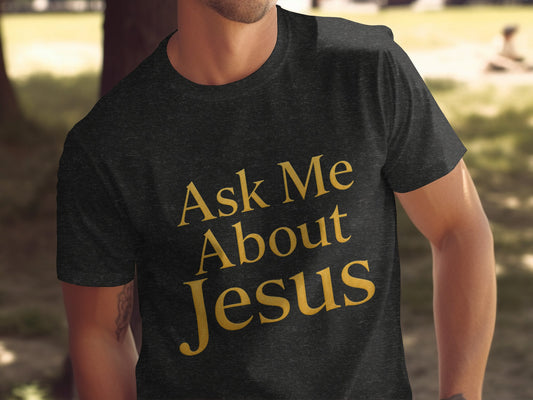 Dark gray t-shirt with gold text that reads "Ask Me About Jesus."