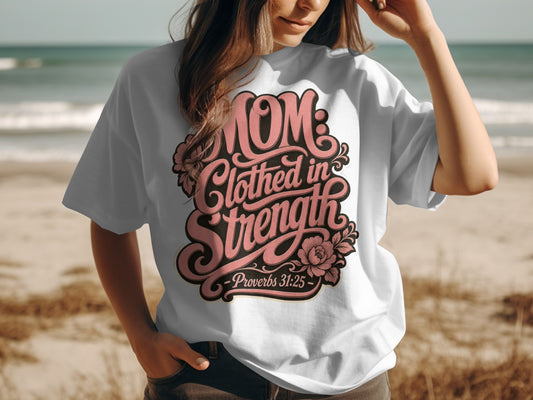 White t-shirt with pink text: "Mom: Clothed in Strength - Proverbs 31:25"