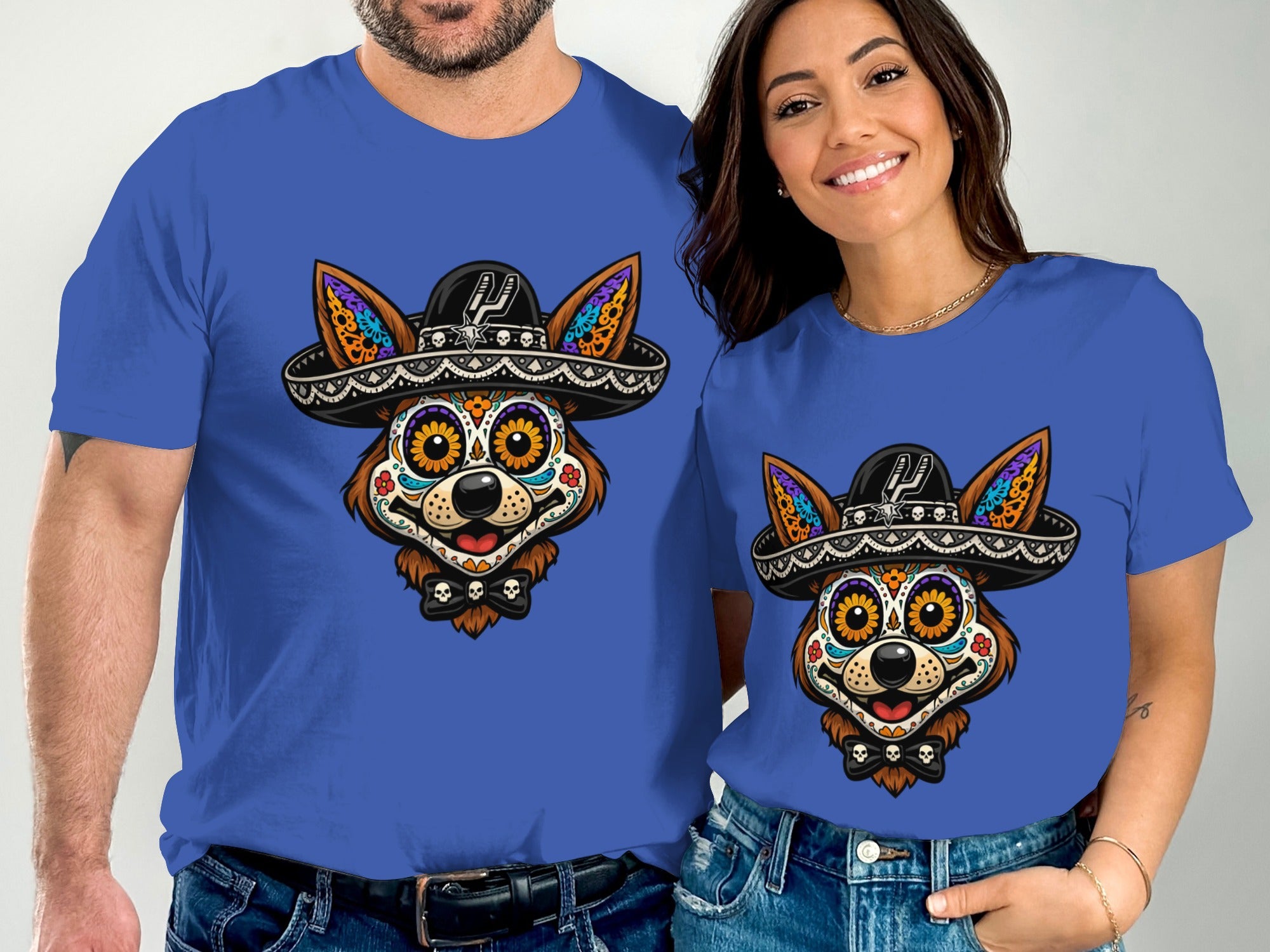 Two people wear blue t-shirts featuring a dog with sugar skull face paint and a sombrero.
