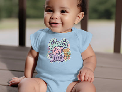 Baby wearing light blue bodysuit with "God's Got This" and a teddy bear.