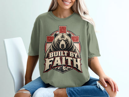 Bear with cross and mountains graphic with "Built by Faith" text on olive green t-shirt.