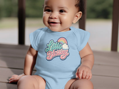 Baby in light blue onesie with "Little Blessing" text and rainbow graphic.