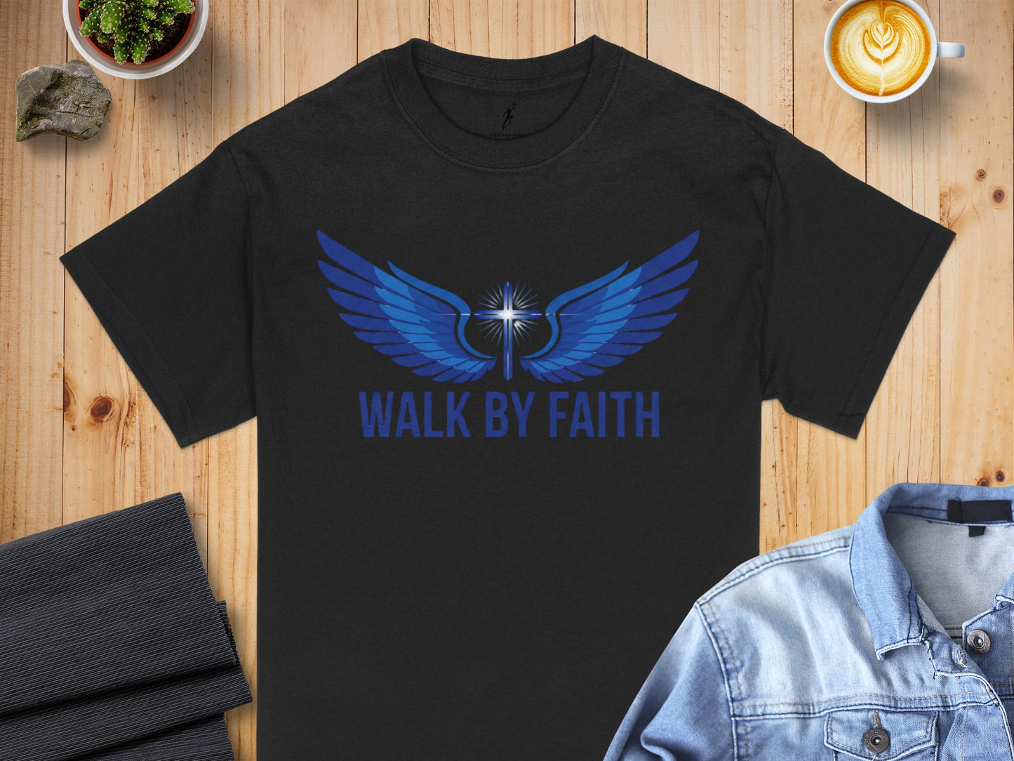 Black t-shirt with blue wings and cross graphic, text "WALK BY FAITH".