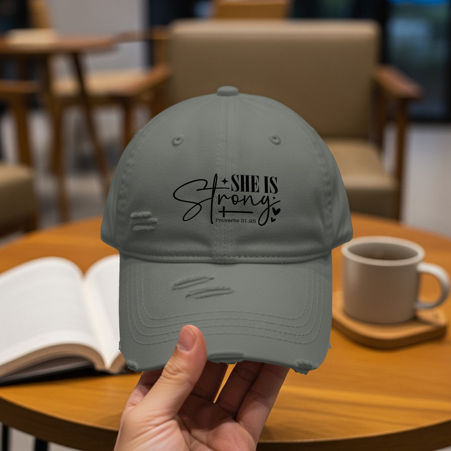 Gray distressed baseball cap with "SHE IS Strong" text and Proverbs 31:25.