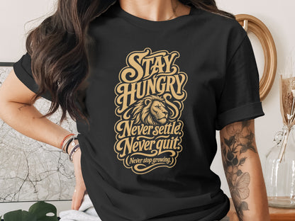 Black t-shirt with gold text: "Stay Hungry Never settle Never quit (Never stop growing.)" and a lion's head.