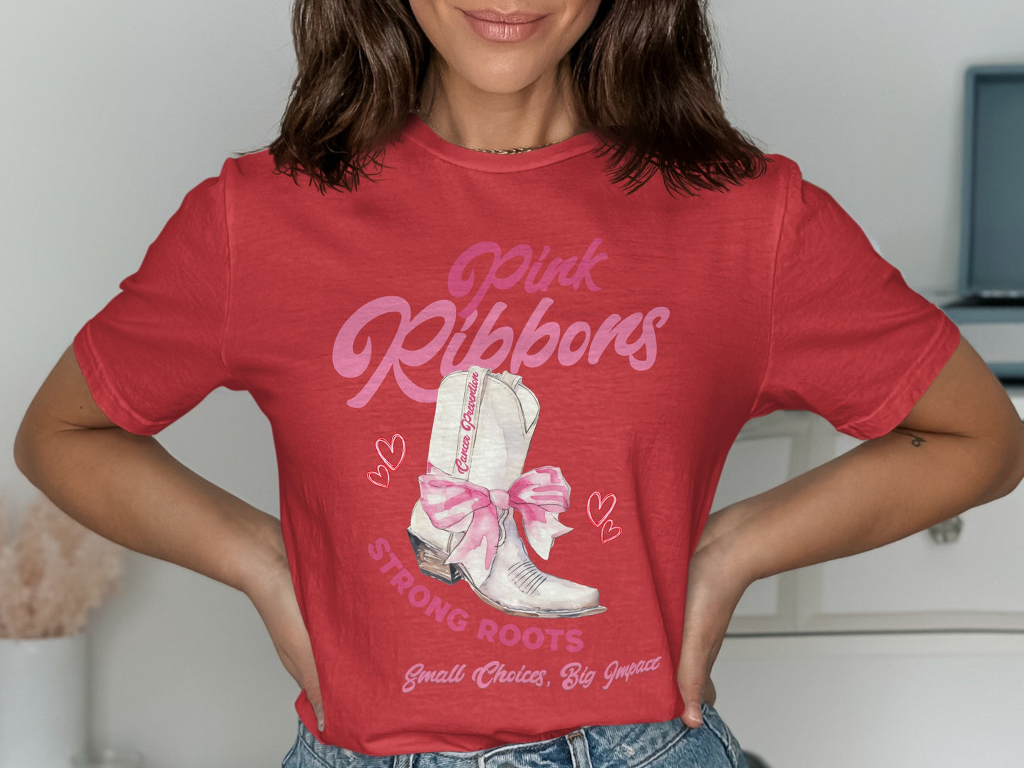 Red t-shirt with white boot, pink ribbon, and text: Pink Ribbons, Strong Roots, Small Choices, Big Impact.