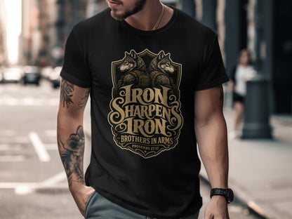 Black t-shirt with gold emblem featuring wolves, text "Iron Sharpens Iron", and "Brothers in Arms".