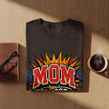 Dark-colored t-shirt with "MOM superhero", text in retro comic book style.