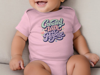 Pink baby onesie with "Created With a Purpose" in colorful retro lettering.