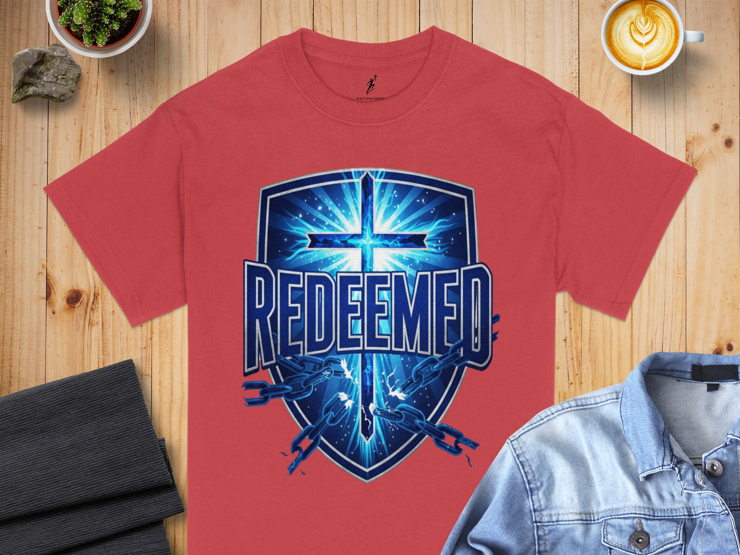 Coral t-shirt with a blue shield graphic featuring a cross and broken chains.