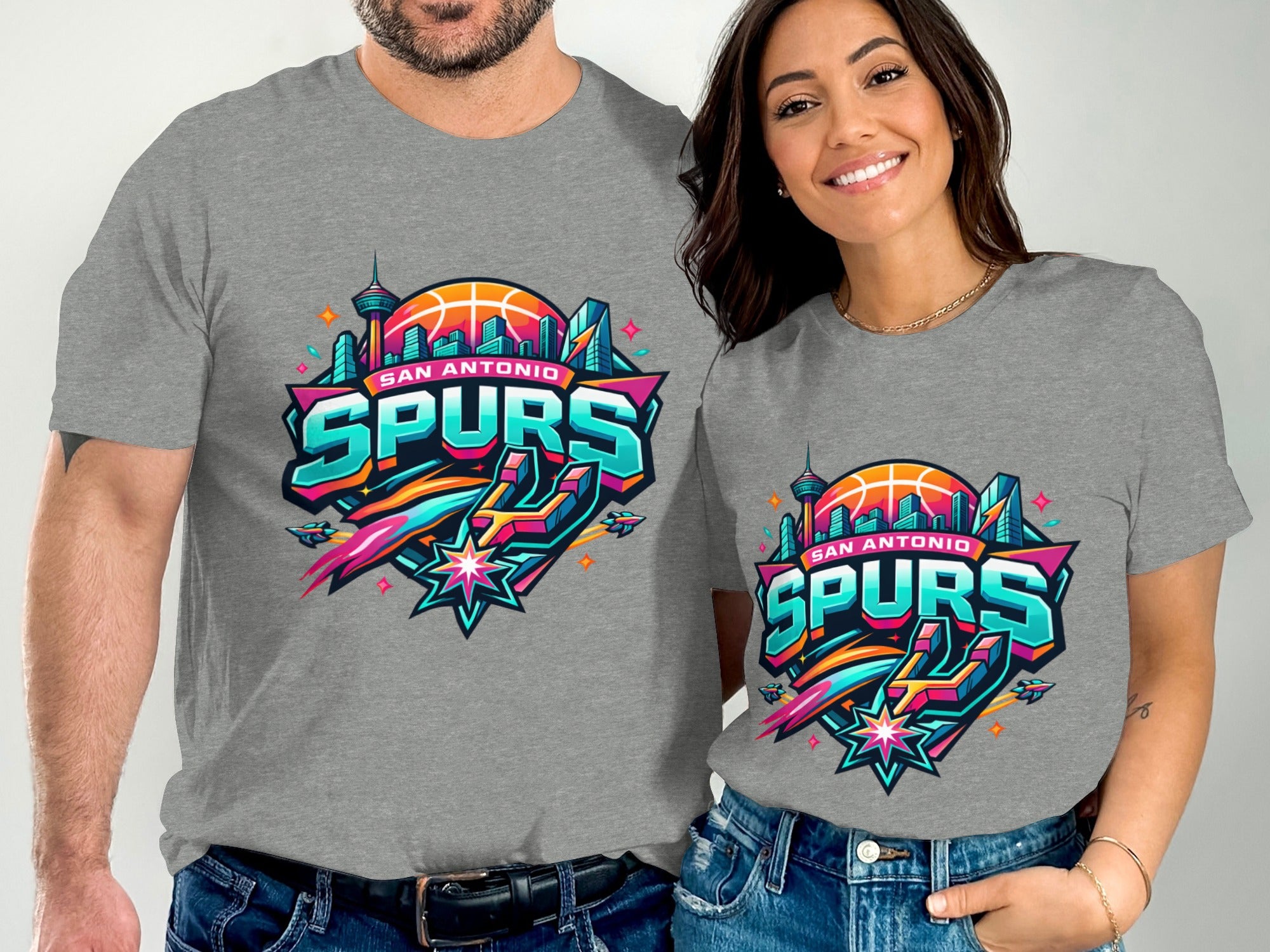 Man and woman wearing grey t-shirts with San Antonio Spurs logo featuring buildings and basketball.