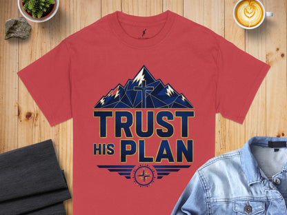 Red t-shirt displays mountains, a cross, and text that reads "TRUST HIS PLAN".