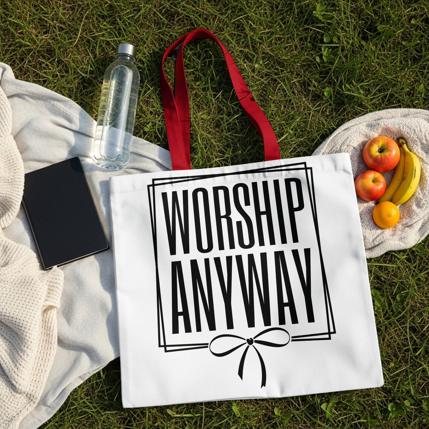 White tote bag with "WORSHIP ANYWAY" text and a ribbon bow design.
