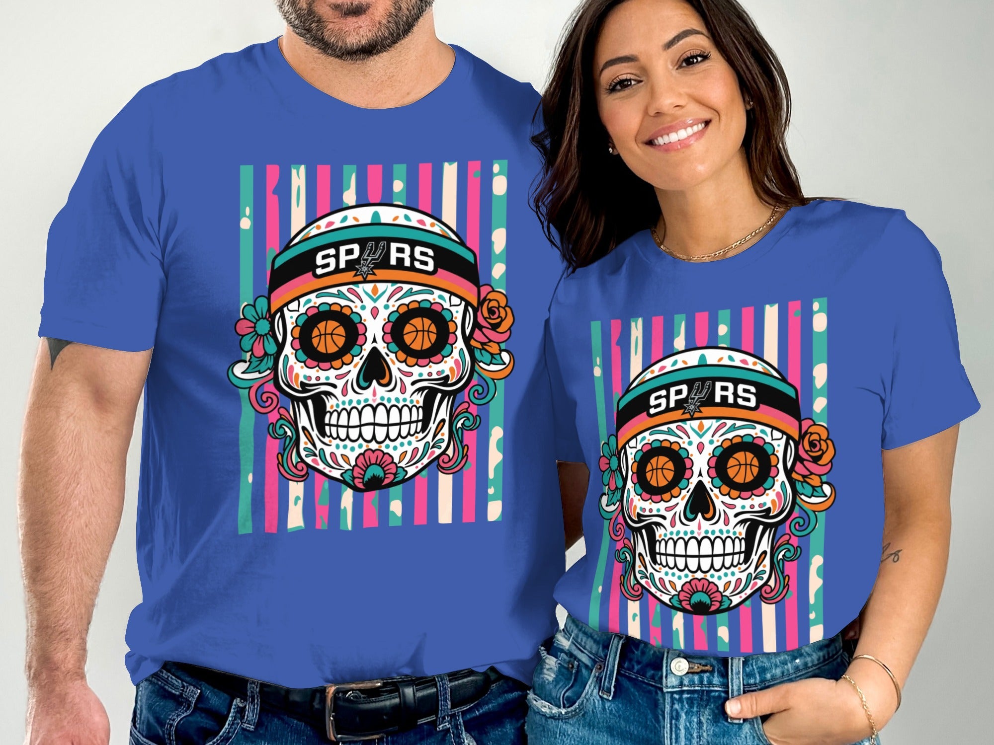 Man and woman wearing blue shirts with Sugar Skull graphic and "SPURS" text.