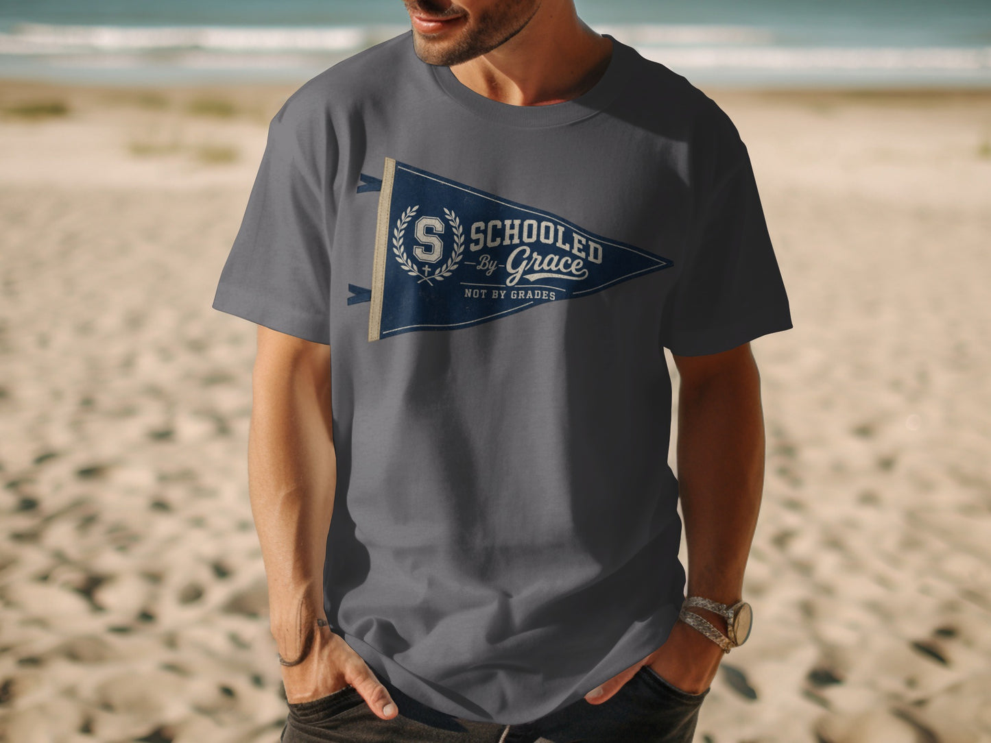Gray t-shirt with a navy blue pennant graphic reading "Schooled By Grace Not By Grades."