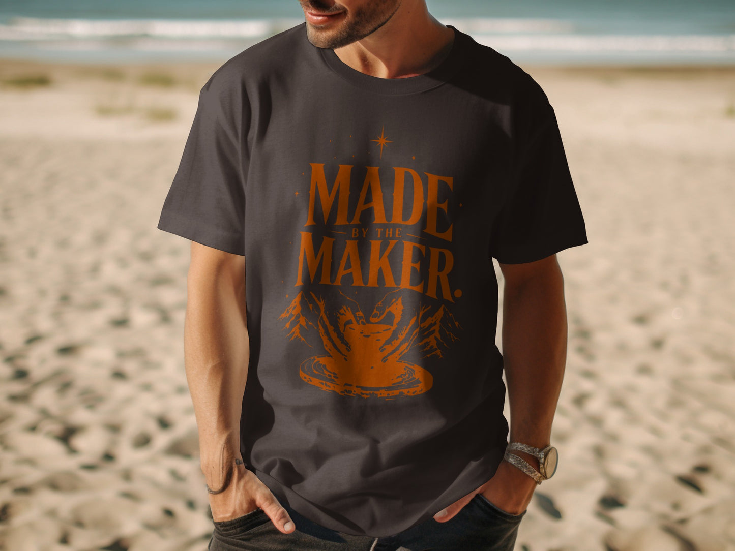 Dark grey t-shirt with orange text "MADE BY THE MAKER" and pottery design.